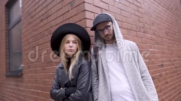 一个女孩和一个男人在城里用砖墙摆姿势在背景上他们看着相机在风格上视频的预览图