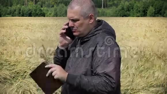 在黄色麦田附近有手机的农民视频的预览图