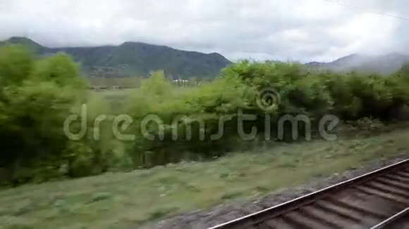 从火车窗口的山谷在白云的背景上躺在葱茏的山脉上高加索格鲁吉亚视频的预览图