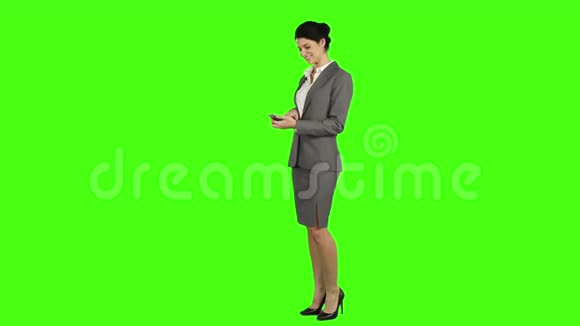 商务女性一边用智能手机一边笑着看着摄像机视频的预览图