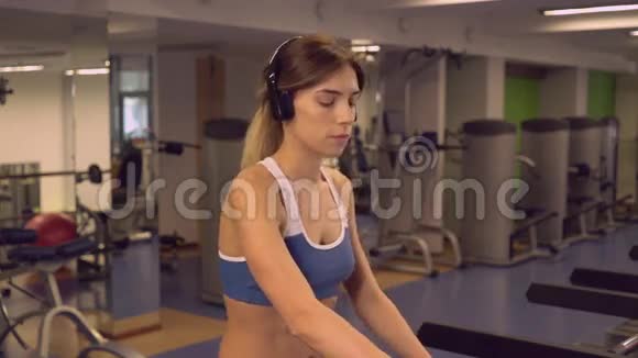 女运动员使用有氧运动机器通过耳机收听播放列表视频的预览图