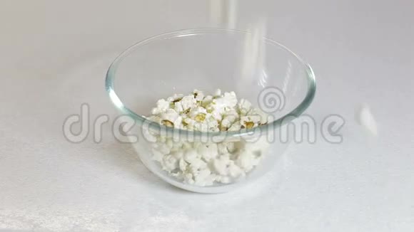 蓬松明亮的爆米花碎片在白色背景下缓慢运动掉进碗里视频的预览图