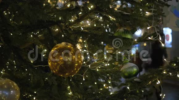 圣诞装饰球挂在树上的背景灯花环上闪亮的黄色球视频的预览图