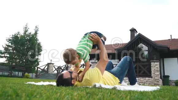 父亲和他的小儿子在夏天公园的草地上玩耍视频的预览图
