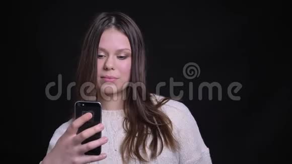 年轻有魅力的白种人深色头发的女性特写照片她在电话里打了个视频电话边说边笑视频的预览图
