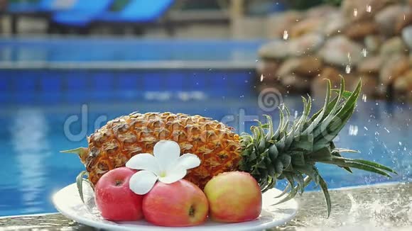 在游泳池后面的菠萝玫瑰苹果和弗兰吉帕尼花上溅起的水花视频的预览图