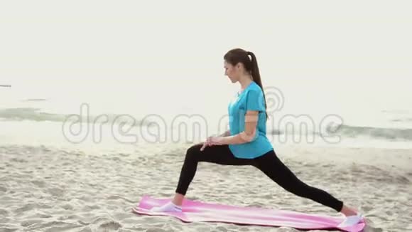 日出时在沙滩上做瑜伽运动的年轻女子视频的预览图