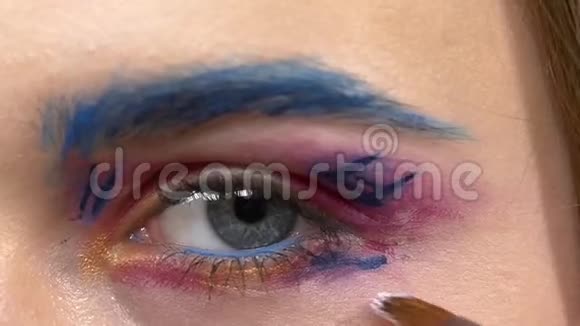 化妆师在模特的眼睛上涂上浅色颜料视频的预览图