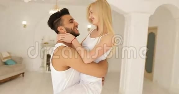 年轻的幸福夫妇拥抱女人奔跑跳过男人拥抱旋转在现代的家庭卧室盘旋视频的预览图