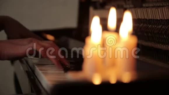 在蜡烛的灯光下特写女性双手在黑暗中弹钢琴视频的预览图