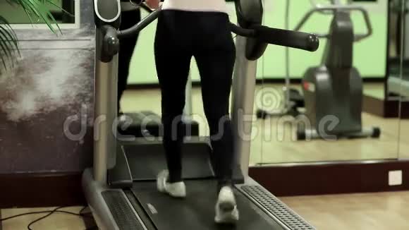 女人在健身房训练在健身房跑步机上行走的女人视频的预览图