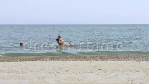 年轻人在沙滩附近的绿松石海里游泳和玩耍视频的预览图