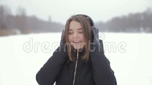 冬天的快乐女孩听着音乐站在雪地里视频的预览图