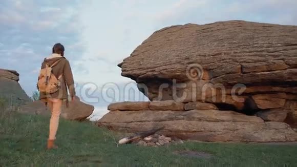 日落时分年轻的旅游女性背包客在岩石上徒步旅行视频的预览图