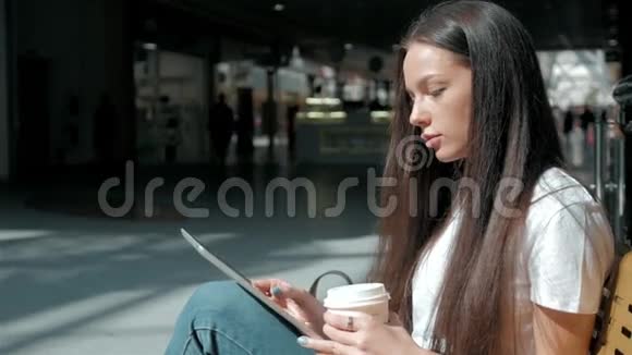 年轻漂亮的学生女孩带着智能手机和咖啡在购物中心视频的预览图