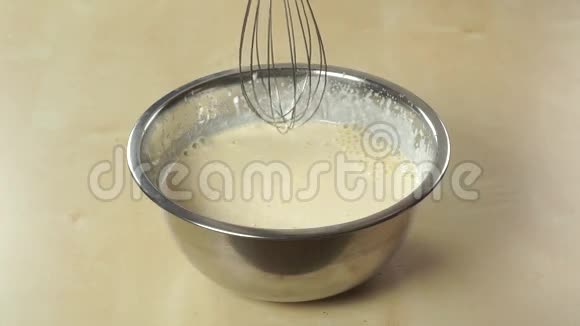 用手提搅拌器在闪亮的钢碗里准备奶油视频的预览图