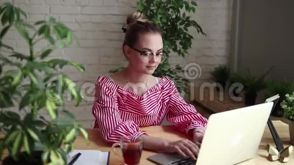 微笑着快乐的商人坐在桌子旁看着笔记本电脑的屏幕有一个视频电话年轻的商人视频的预览图