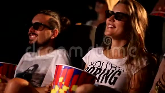 一群迷人的年轻兴奋的快乐女性男性朋友吃爆米花享受3d4d动作电影院视频的预览图