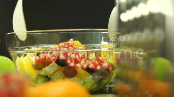 漂亮的女孩把水果沙拉拌在玻璃碗里视频的预览图