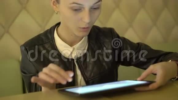把坐在咖啡馆里的漂亮女孩用平板电脑和微笑4K视频的预览图