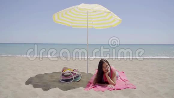 年轻女士躺在沙滩毛毯上视频的预览图