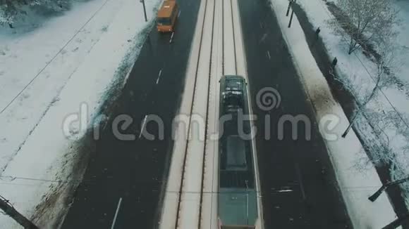 在冬季森林道路上的顶部可以看到汽车和电车雪花空中无人机镜头视频的预览图