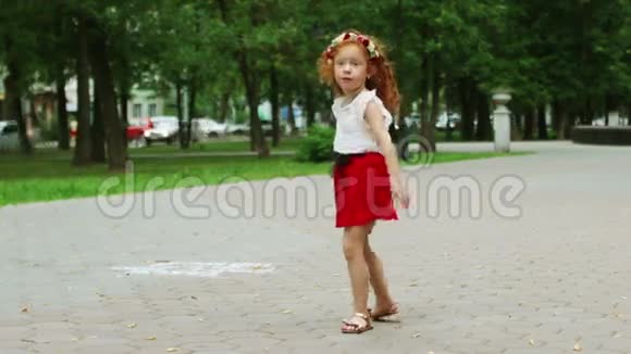 一个红头发的小女孩在绿色公园跳舞视频的预览图