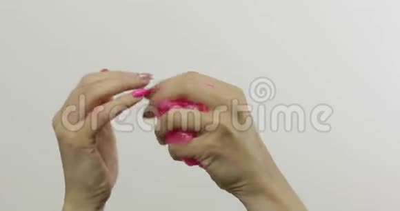 女人的手在白色背景上玩着奇怪的令人满意的粉红色黏液抗压力视频的预览图