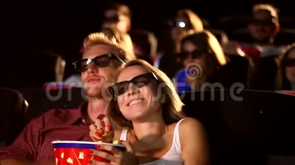 一群年轻兴奋迷人的男性女性朋友吃爆米花享受3d4d动作电影院视频的预览图