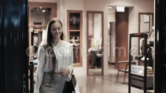漂亮的商务女性穿着豪华西装在购物中心漫步时背着购物袋视频的预览图