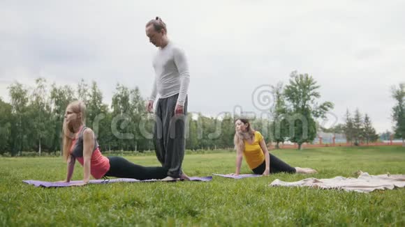 早上公园的瑜伽教练训练年轻女性的灵活性视频的预览图