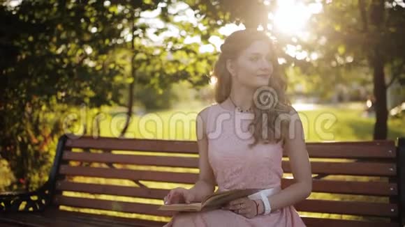 年轻女子坐在公园的长凳上看书一个漂亮的欧洲女孩带着书在学视频的预览图