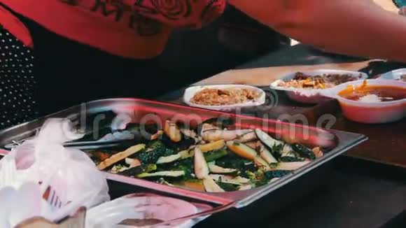柜台上的女人用塑料盘子分发食物里面有汤和粥附近有黄瓜视频的预览图