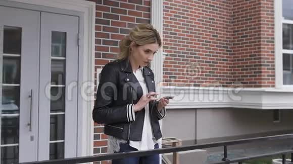 城市生活方式时尚的女孩使用手机短信智能手机应用程序在街道上金发女郎视频的预览图