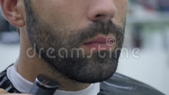 口渴的过程理发师给一个留胡子的年轻人理发的特写视频的预览图