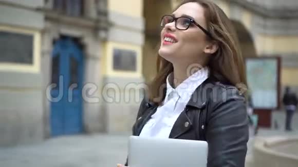 漂亮的黑发女人走在街上拿着笔记本电脑视频的预览图