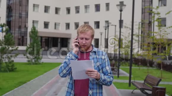 一个年轻的学生来到大学的背景下打电话拿着重要的文件视频的预览图
