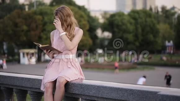 夏天公园喷泉里一个年轻迷人的女孩饶有兴致地读着一本书视频的预览图