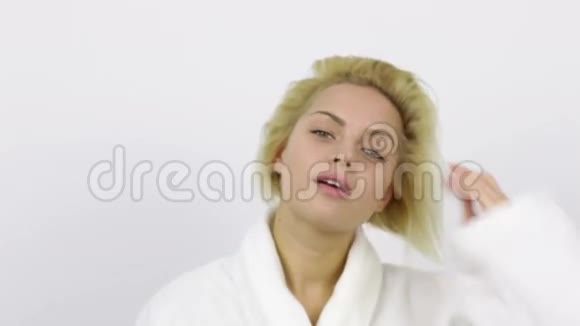 金发女人穿白色浴袍照镜子视频的预览图