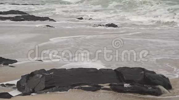 波浪在岩石和沙滩上阴天拍摄慢动作视频视频的预览图