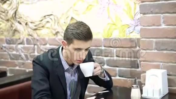 商人在咖啡馆里拿着手机喝着一杯咖啡视频的预览图