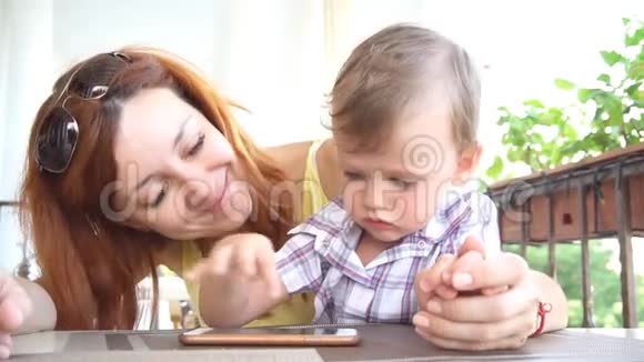 一个和妈妈在一起的小男孩用智能手机上网视频的预览图