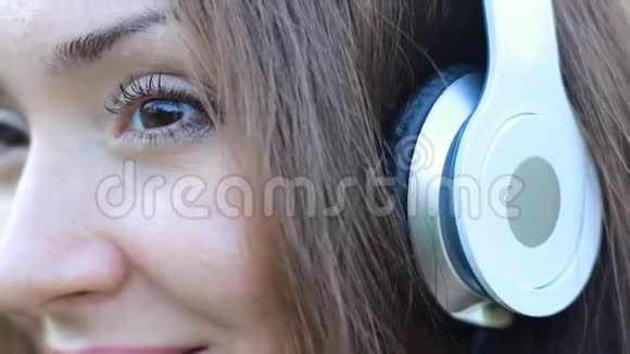 女人在户外用耳机听音乐一个漂亮的特写女孩的肖像视频的预览图