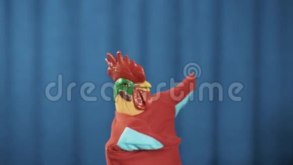 鸡手木偶跳舞拍手和鞠躬与蓝色窗帘背景视频的预览图