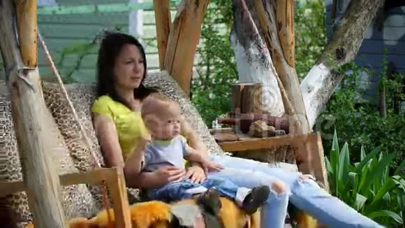 年轻漂亮的妈妈和一个小儿子骑着秋千视频的预览图