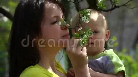 漂亮的年轻母亲和一个年轻的儿子欣赏着开花的树视频的预览图