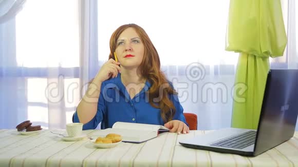 一个棕色头发的女人在一张桌子旁的咖啡馆里工作喝咖啡视频的预览图