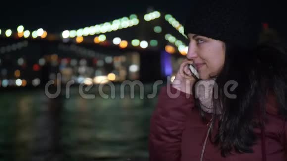 年轻女子晚上在布鲁克林大桥打电话视频的预览图