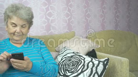 使用手机的老年妇女坐在沙发上视频的预览图