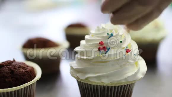 用奶油装饰巧克力纸杯蛋糕用手轻轻地洒在新鲜的纸杯蛋糕上视频的预览图
